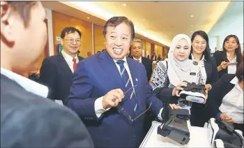  ??  ?? Abang Johari looks delighted after trying out a gadget when touring the exhibition area outside the congress hall. Dr Jamilah is at third right.