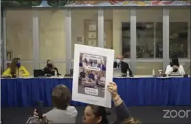  ?? IMAGE FROM SCREENSHOT ?? A protestor at the Feb. 22Spring-Ford meeting holds up a sign as the school board president calls for a vote to adjourn the meeting due to crowd noise.