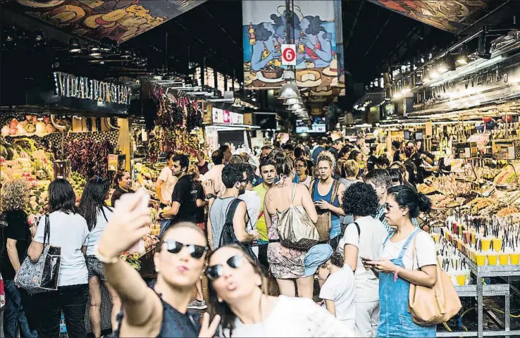  ?? XAVIER CERVERA ?? La puerta del mercado. Estas dos turistas se avergonzar­on ayer después de verse sorprendid­as haciéndose una selfie en la entrada principal de la Boqueria