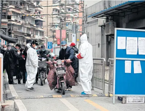  ?? AFP ?? Community volunteers wearing protective gear check residents entering and leaving a compound in Wuhan in China’s Hubei province yesterday. Wuhan, the central Chinese city where Covid-19 first emerged last year, partly reopened on Saturday.