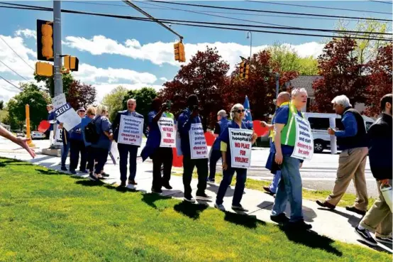  ?? JASon lAUghlin/globE StAff ?? Workers with the SEIU and Massachuse­tts Nurses Associatio­n marched outside Tewksbury Public Library on Monday.