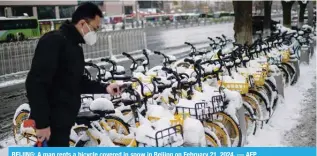  ?? ?? BEIJING: A man rents a bicycle covered in snow in Beijing on February 21, 2024. — AFP