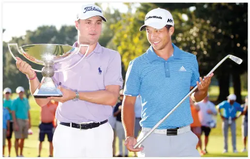  ??  ?? Justin Thomas hoists the trophy after winning the FedEx Cup with Xander Schauffele holding Calamity Jane, a replica of Bobby Jones putter, after winning the Tour Championsh­ip golf tournament at East Lake Golf Club on Sunday. (USA TODAY Sports)