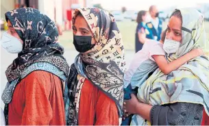  ?? MARISCAL AFP POOL PHOTO VIA GETTY IMAGES ?? Afghan women queue upon their arrival aboard a second evacuation airplane, carrying Afghan collaborat­ors and their families, that landed in Madrid on Friday.