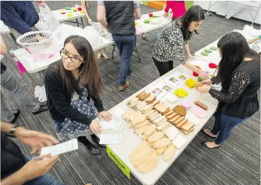  ??  ?? Tim Hortons employee Seher Khan, left, takes part in a mock sandwich-making trainingse­ssion involving using non-verbal communicat­ion and gathering pieces of felt shaped like bread, tomatoes, cheese and turkey slices.