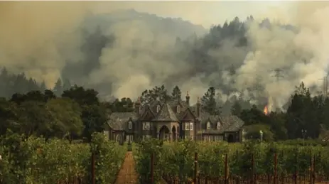  ?? JAE C. HONG/THE ASSOCIATED PRESS ?? A wildfire burns behind a winery Saturday in Santa Rosa, Calif. Firefighte­rs say strong winds are making it more difficult to contain the blaze.