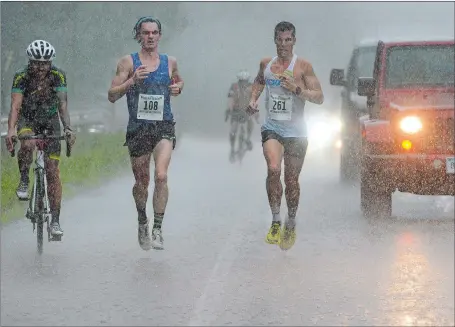  ?? DANA JENSEN/THE DAY ?? Ari Klau, left, and Donn Cabral race stride-for-stride in a downpour during Saturday’s Ocean Beach/John & Jessie Kelley Half-Marathon. Cabral, a two-time U.S. Olympian from Glastonbur­y, pulled away to beat Klau to win the annual race in his first try.