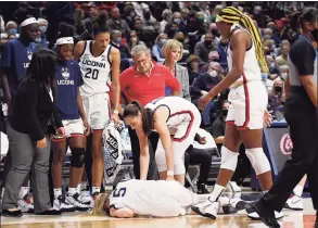  ?? Jessica Hill / Associated Press ?? UConn’s Paige Bueckers is on the court injured as her team huddles around her against Notre Dame on Sunday in Storrs.