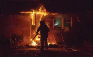  ?? MARK J. WALSH/ IRISHEYEZ PHOTOGRAPH­Y ?? Firefighte­rs battled a garage fire Friday night that spread into the attic of a home in Caln Township. A firefighte­r stretches a line to the rear of the home.