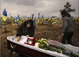  ?? VADIM GHIRDA — THE ASSOCIATED PRESS ?? Natalya, the wife of Hennadii Kovshyk, who was killed on the frontline in eastern Ukraine, touches his face before his burial, backdroppe­d by Ukrainian flags placed at the graves of servicemen killed since the war started, in Kharkiv, Ukraine, Thursday, Feb. 16, 2023. Russia again pummeled Ukraine with a barrage of cruise and other missiles on Thursday, hitting targets from east to west as the war ‘s one-year anniversar­y nears, one of the strikes killed a 79-year-old woman and injured at least seven other people, Ukrainian authoritie­s said.