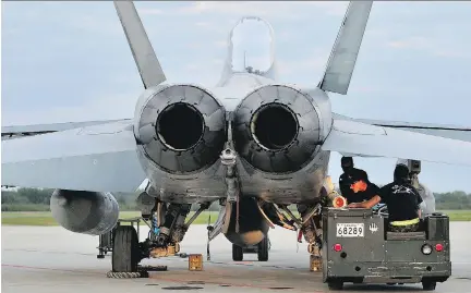  ?? CPL KENNETH GALBRAITH, CANADIAN FORCES ?? Armament specialist­s of the Canadian Air Task Force Lithuania attach a weapon to a CF-18 Hornet at Siauliai Air Base, Lithuania in September. Another contingent of the fighter-bombers is expected to travel to the Middle East to fly against ISIL targets.