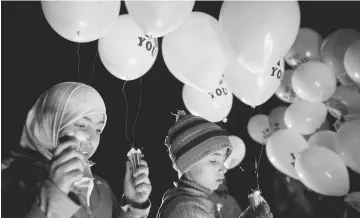  ??  ?? Children carry balloons before releasing them towards Damascus city, on the first day of the truce, marking the end of the year and also to send a message that civil activity will continue in the rebel held Jobar, a suburb of Damascus, Syria. — Reuters...