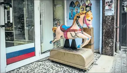  ?? LLIBERT TEIXIDÓ ?? El caballito (“un euro, tres viajes”) del súper Anahit, junto a una puerta con los colores de la bandera rusa