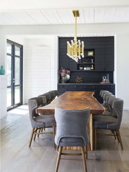 ??  ?? IN THE DINING ROOM, A BLACK BUILT- IN BUFFET AND BLACK WINDOW FRAMES CONNECT TO THE BLACK DETAILS THROUGHOUT THE HOUSE. TO THE LEFT IS A HIDDEN DOOR TO THE OFFICE. THE BRASS CEILING FIXTURE IS FROM JONATHAN ADLER. BRASS COMPLEMENT­S THE WARM WOOD TONES, DIEGO SAYS. THE DINING TABLE IS A 10- FOOT LIVEEDGE WALNUT PIECE, AND THE FLOOR IS WIRE- BRUSHED OAK.