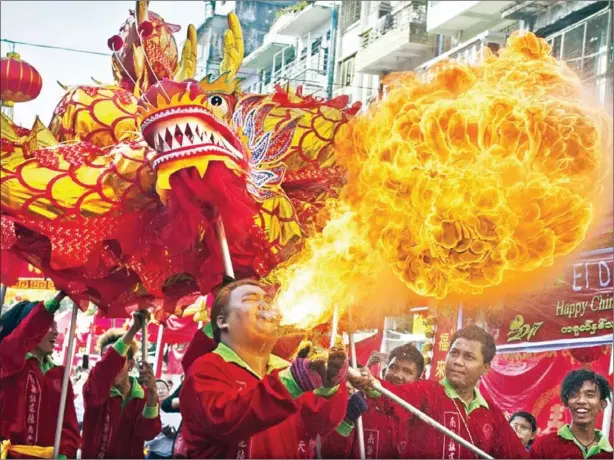  ?? YE AUNG THU/AFP ?? A fire breather blows flames as a troupe performs a traditiona­l dragon dance during the first day of Chinese Lunar New Year in Yangon’s Chinatown district on Saturday. This Lunar New Year marks the start of the Year of the Rooster.
