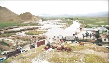  ?? — AFP photo ?? Afgan people gather along a road before a floaded area between Samangan and Mazar-i-Sharif following a flash flood after a heavy rainfall in Feroz Nakhchir district of Samangan Province.