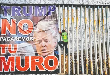  ?? GUILLERMO ARIAS / AFP via
Gett
y Images ?? A man hangs a banner reading “Trump we will not pay for your wall” at a protest at the
U. S.-mexico border in Playas de Tijuana, Baja California, earlier this month.