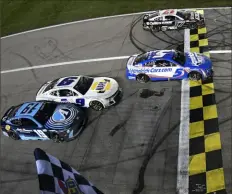  ?? Logan Riely/Getty Images ?? Kyle Larson, center, takes the checkered flag over Chris Buescher, top, to win the NASCAR Cup Series AdventHeal­th 400 at Kansas Speedway in Kansas City, Kans.