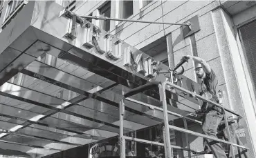  ?? Seth Wenig / Associated Press file photo ?? A worker removes letters from the awning of a building in 2016 formerly known as Trump Place in New York after hundreds of tenants signed a petition saying they were embarrasse­d.