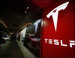  ?? (AP file photo) ?? The company logo hangs outside the door to a Tesla store at Cherry Creek Mall in Denver in 2019. A Tesla using its partially automated driving system slammed into a Florida Highway Patrol cruiser Saturday on an interstate near downtown Orlando.