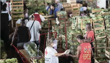  ?? SILVIA IZQUIERDO AP ?? A member of the Red Cross applies disinfecta­nt to a worker at the wholesale market CEASA in Rio de Janeiro, Brazil.