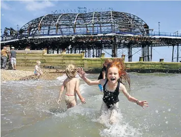  ?? Picture: REUTERS ?? Lily Blackburn, 7, plays with friends in the sea near the burnt-out remains of a section of Eastbourne pier on England’s south coast. A fire broke out in the Victorian pier’s amusement arcade on Wednesday. The government has already promised about...