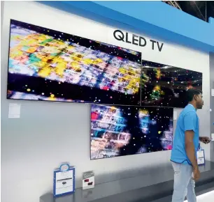  ?? — Photos by Dhes Handumon ?? THE BIG AND SMALL OF IT: Samsung QLed TVs are quite the rage among visitors; right, a salesperso­n displays how an airfryer works on the fourth day of Gitex Shopper on Tuesday.