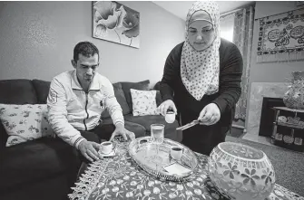  ?? Melissa Phillip / Staff photograph­er ?? Mohamad Khir Alakish and his wife, Amal Karkoura, have coffee in their Gulfton-area apartment. The couple and their three children get by on the $17,000 a year he earns as a cook.