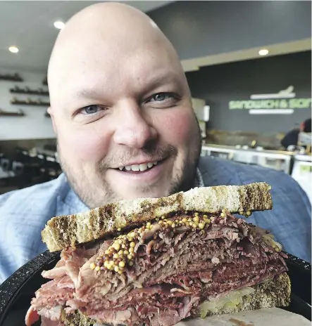  ?? ED KAISER ?? Jimmy Shewchuk holds a Montreal smoked meat sandwich, one of the signature dishes at his eatery, Sandwich and Sons, at 13119 156 St. Shewchuk says his “working class” customers know a lot about food.