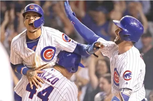  ?? GETTY IMAGES ?? Improvemen­t at the plate has made Javy Baez (shown getting a lift from Anthony Rizzo and congratula­tions from Kris Bryant) a three-discipline star.