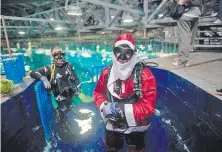  ?? ?? El buzo Felipe Luna, en la época navideña, alimenta a los tiburones del acuario de Río de Janeiro vestido de Papá Noel.