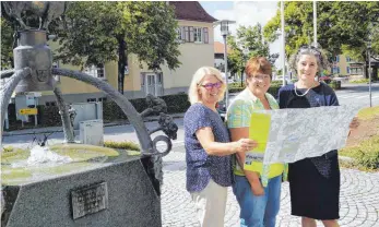  ?? FOTOS: MARLENE GEMPP ?? Antje Böse vom Gästeamt Argenbühl, Beurens Ortsvorste­herin Silvia Ullrich und Margret Kaiser vom Isny Marketing (von links) haben an der Karte mitgearbei­tet. Sie stehen an einem Startpunkt einer Wanderrout­e vor dem Eisenharze­r Rathaus.