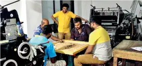  ?? ?? Playing carrom to while away the time: ‘Soft Top Printers’ owner Roshan Liyanage (centre) and his staff. Pix by Indika Handuwala