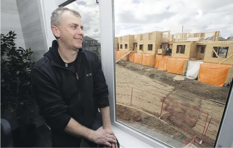  ?? DAVID BLOOM ?? Rafal Klonowski looks out the window of the Oakmont Townhomes developmen­t show home in northeast St. Albert. He and his wife, Amy, have purchased a home here.