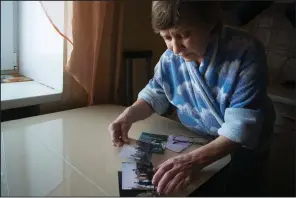  ?? AP/NATALIYA VASILYEVA ?? Farkhanur Gavrilova looks at photos of her son, Ruslan Gavrilov, one of seven men from the village of Kedrovoye, Russia, who are believed to have joined a private military company involved in an attack on U.S.-backed Kurdish fighters in Syria.