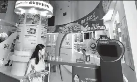  ?? PROVIDED TO CHINA DAILY ?? A visitor walks past Nestle’s booth at an exhibition of dairy products held in Beijing.