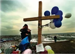  ?? Associated Press ?? ■ Students embrace each other April 24, 1999, at a makeshift memorial for their slain classmates at Columbine High School on a hilltop overlookin­g the school in Littleton, Colo. Twelve students and one teacher were killed in a murderous rampage at the school on April 20, 1999, by two students who killed themselves in the aftermath.