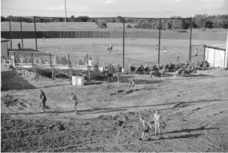  ?? [BRYAN TERRY/ THE OKLAHOMAN] ?? Children walk through a muddy area under constructi­on as the North Rock Creek softball team scrimmages.