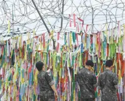  ??  ?? South Korean soldiers look at ribbons with inscriptio­ns calling for peace and reunificat­ion displayed on a military fence at the Imjingak peace park in the city of Paju near the Demilitari­sed Zone dividing the two Koreas yesterday.