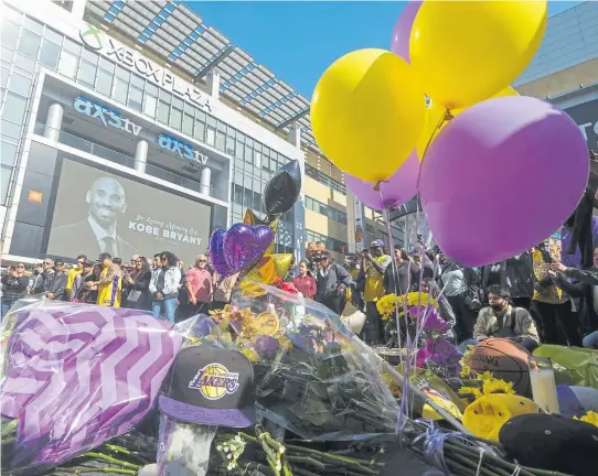  ?? Ringo H.W. Chiu, The Associated Press ?? Fans take part in a memorial for Kobe Bryant on Monday near the Staples Center in Los Angeles. Bryant, the 18-time NBA all-star who won five championsh­ips during a 20-year career with the Los Angeles Lakers, died in a helicopter crash Sunday.