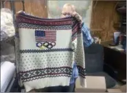  ??  ?? Debbie McDermott holds up the back side of a Ralph Lauren sweater that athletes wore for the 2014 Winter Olympics closing ceremony. The sweater was made using Shepherd’s Wool, one of Stonehedge Fiber Mill’s yarn lines.