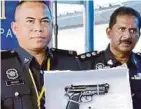  ??  ?? ROSLEY (kiri) menunjukka­n sepucuk pistol tiruan yang dirampas daripada Geng Saudara selepas ditahan di Kampung Baru, Luyang.