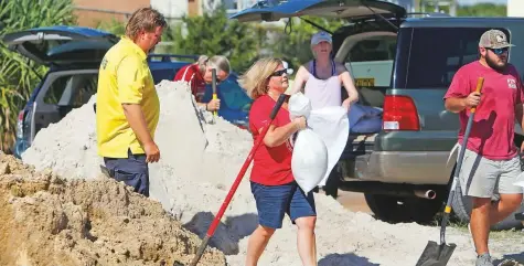  ?? AP ?? Residents fill sand bags at the Isle of Palms municipal lot where the city was giving away free sand in preparatio­n for Hurricane Florence at the Isle of Palms in South Carolina on Monday.
