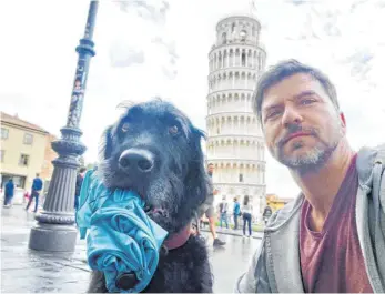  ?? FOTO: KRISS RUDOLPH ?? Kriss Rudolph mit seinem Labrador-Mischling Mompa vor dem Schiefen Turm in Pisa – der Hund verträgt das Fliegen gut.