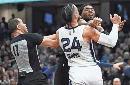  ?? KEN BLAZE/USA TODAY SPORTS ?? The Cleveland Cavaliers’ Donovan Mitchell throws a punch at the Memphis Grizzlies’ Dillon Brooks (24) as referee Jonathan Sterling tries to break up the fracas during the second half at Rocket Mortgage Fieldhouse on Thursday. Both players were ejected. The Cavaliers went on to win the game 128-113.