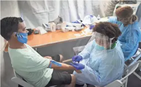  ?? JOE RAEDLE/GETTY IMAGES ?? A doctor tests for COVID-19 in Miami Lakes, Fla.