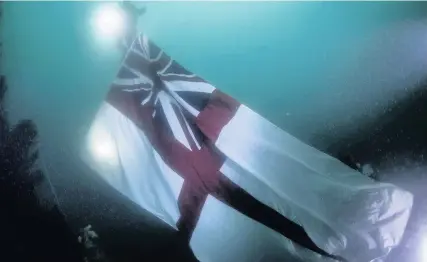  ?? Marjo Tynkkynen/MS Vanguard Expe ?? > HMS Vanguard’s new White Ensign being placed on the wreck in Scapa Flow