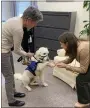  ?? ?? Offering her paw in a show of affection, Nutmeg greets Montgomery County President Judge Carolyn Tornetta Carluccio, on right. Handler Mary Anders is on