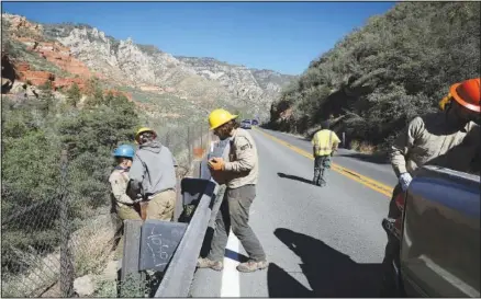  ?? ?? An Arizona Conservati­on Corps crew fills in holes in the fence along Highway 89A in Oak Creek Canyon.