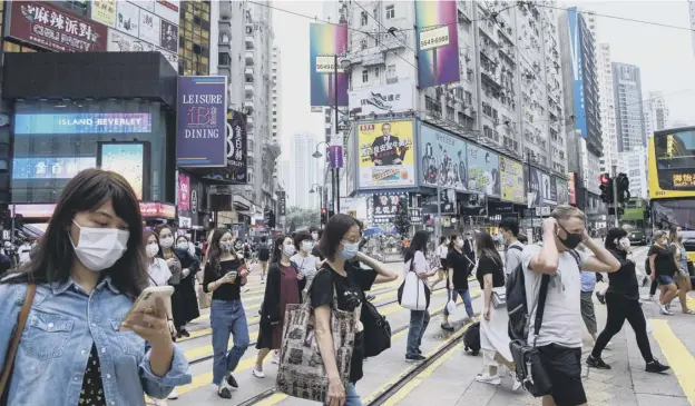  ?? PICTURE: AFP ?? 0 Pedestrian­s in Hong Kong where two people tested positive for coronaviru­s yesterday, ending a 24-day run of no new local cases